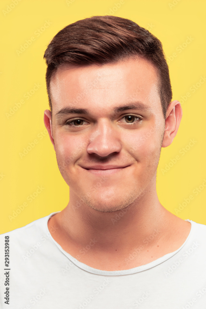Fototapeta premium Caucasian young man's close up portrait on yellow studio background. Beautiful male model with well-kept skin. Concept of human emotions, facial expression, sales, ad. Smiling, looking at camera.
