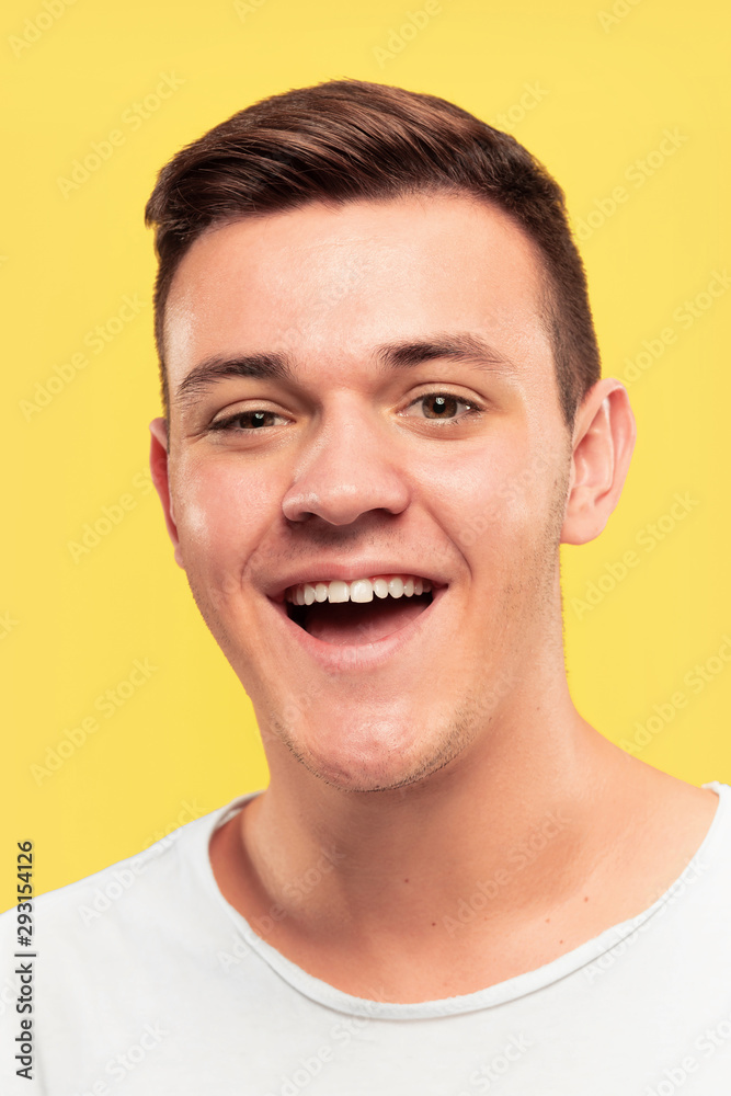 Fototapeta premium Caucasian young man's close up portrait on yellow studio background. Beautiful male model with well-kept skin. Concept of human emotions, facial expression, sales, ad. Smiling, laughting.