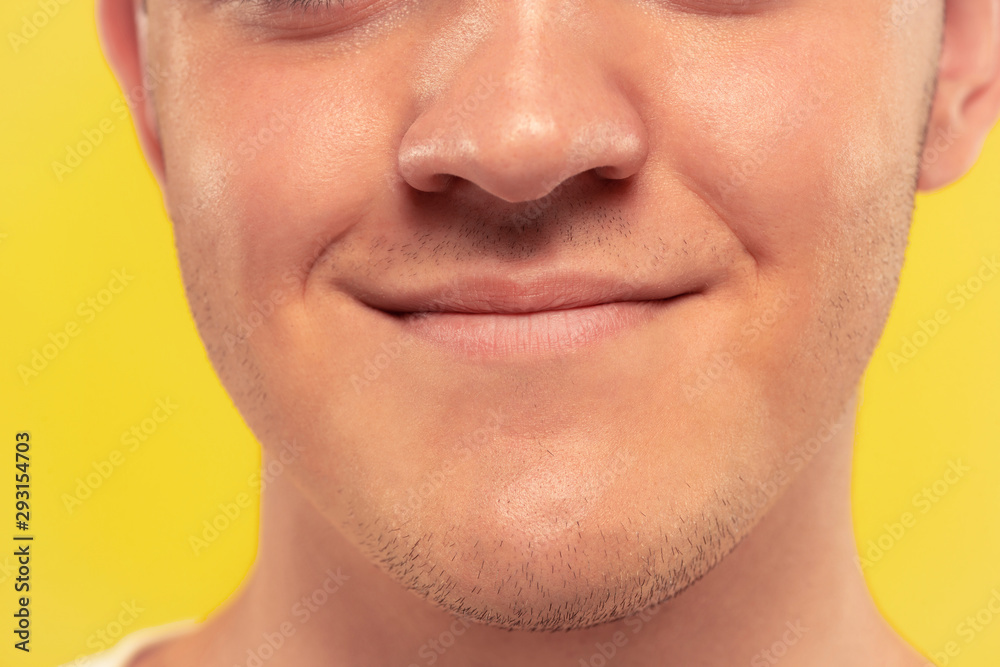Caucasian young man's close up portrait on yellow studio background. Beautiful male model with well-kept skin. Concept of human emotions, facial expression, sales, ad. Lips and cheeks, smiling.