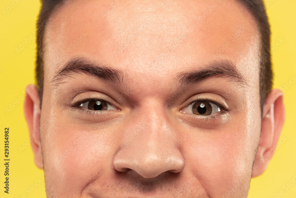 Obraz premium Caucasian young man's close up portrait on yellow studio background. Beautiful male model with well-kept skin. Concept of human emotions, facial expression, sales, ad. Eyes looking at camera.