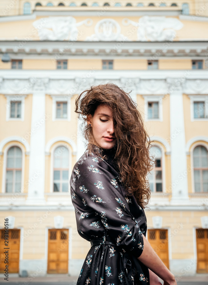 portrait of a young sexy woman with wavy hair on the background of an old yellow building