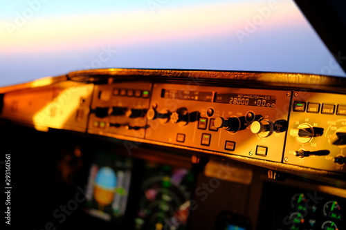 Airbus A320 flight deck and cockpit during flight. Overhead panel, flight control unit, PFD and ND visible. Integrity light and flood light. Lighting of the instruments at sunset and night.