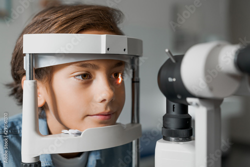 Close up shot of boy checking vision with tonometer at eye clinic photo