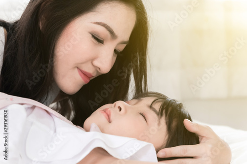 Beautiful mother is embracing her daugher while sleeping on bed happily.