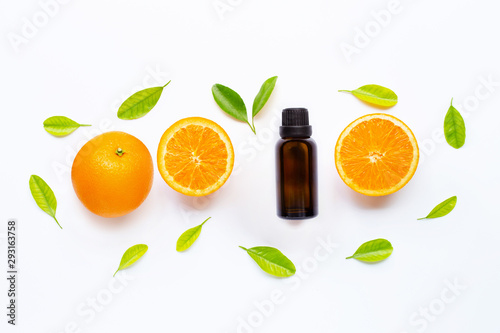 Essential oil with fresh orange fruit and green leaves on white background.