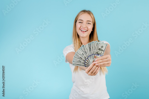pretty young blonde girl with dollard bills isolated over blue