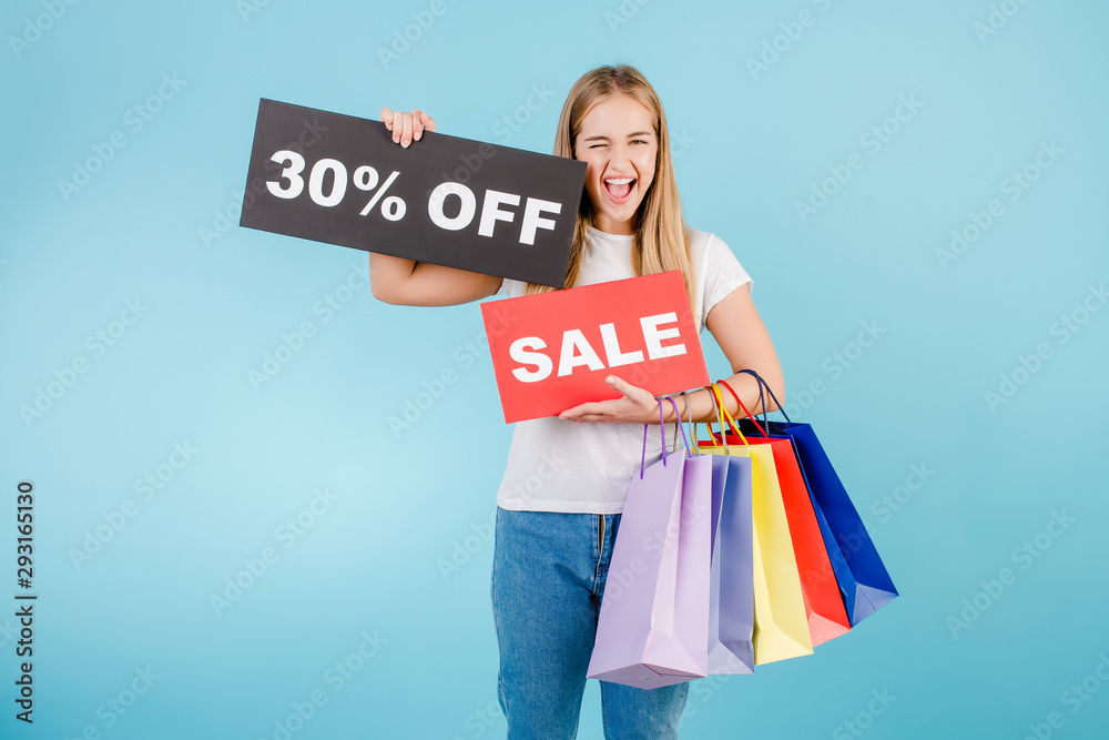 happy screaming blonde woman with 30% off sale sign and colorful shopping bags isolated over blue happy screaming blonde woman with 30% off sale sign and colorful shopping bags isolated over blue