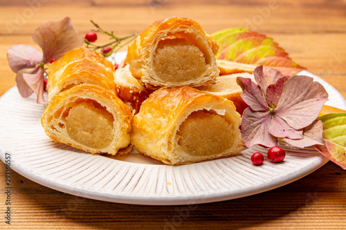 Fresh baked Dutch filled spicy cookies from puff pastry with almonds in autumn colors on dark wooden background