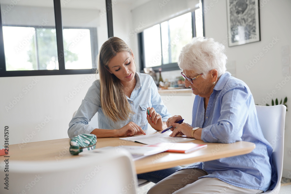 Obraz premium Homehelp assisting elderly woman with paperwork