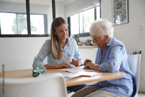 Homehelp assisting elderly woman with paperwork photo
