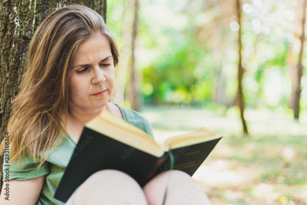 Obraz premium Young woman reading a book outdoors