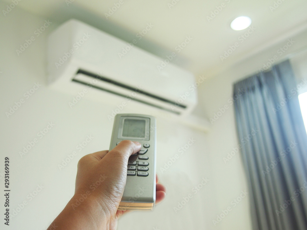 Man using hand remote control adjusting and regulating temperature the air conditioner for energy savings Man using hand remote control adjusting and regulating temperature the air conditioner for energy savings