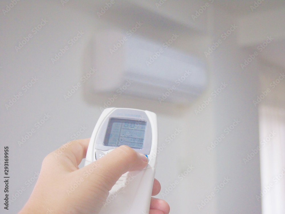 Man using hand remote control adjusting and regulating temperature the air conditioner for energy savings Man using hand remote control adjusting and regulating temperature the air conditioner for energy savings