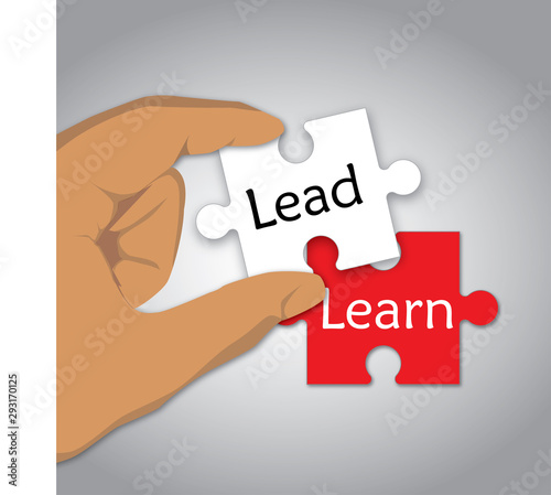 Lead and Learn concept using two pieces of puzzle, one in red with Learn word on it, another piece held by a hand in white with Lead word on it. Leadership concept. 