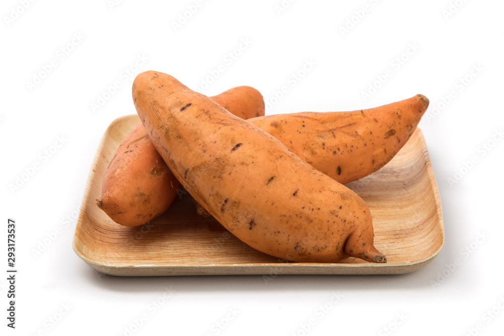 a pile of sweet potatoes on a wooden bamboo plate isolated on white a pile of sweet potatoes on a wooden bamboo plate isolated on white
