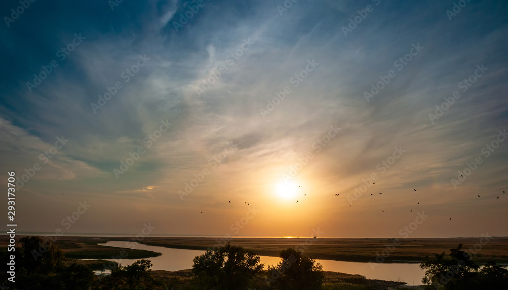 Sunset over the river and flying birds