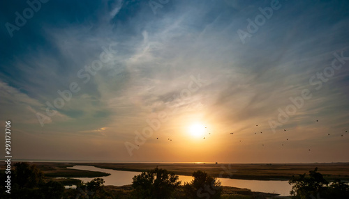 Sunset over the river and flying birds