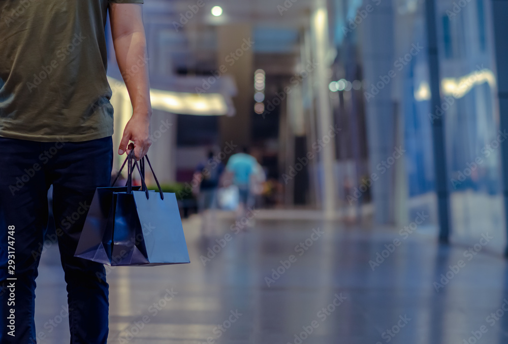 Naklejka premium Man holding shopping bags with shopping mall background. Black Friday shopping sale concept.