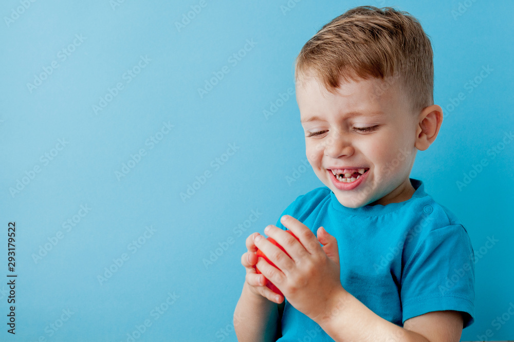 Little kid holding pepper in his hands on blue background. Vegan and healthy concept Little kid holding pepper in his hands on blue background. Vegan and healthy concept