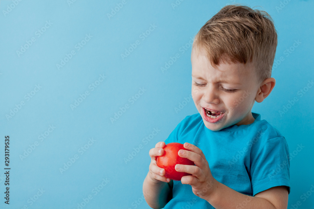 Little kid holding pepper in his hands on blue background. Vegan and healthy concept Little kid holding pepper in his hands on blue background. Vegan and healthy concept