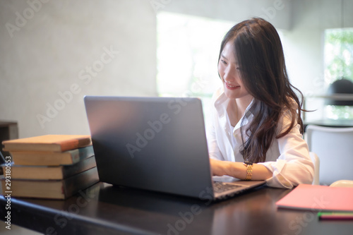 Young Asian woman using laptop computer and tablet PC to working in the modern co working space