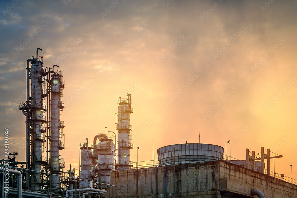 Equipment of industrial plant with sunset sky background, Gas distillation tower and cooling tower in factory of petrochemical plant on yellow sky sunset background