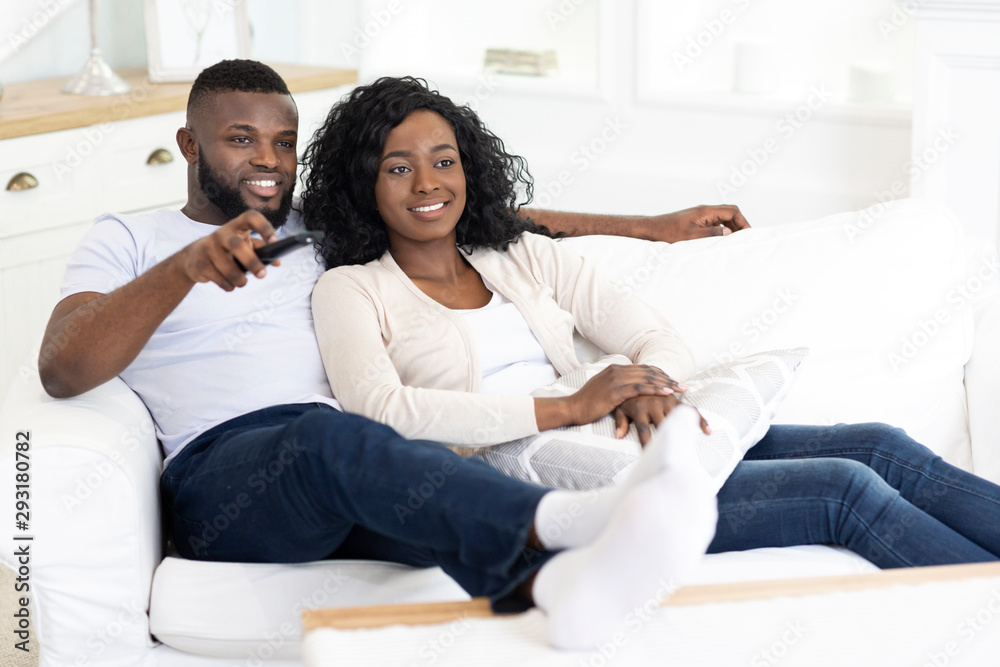 Afro couple relaxing on couch at home and watching tv Afro couple relaxing on couch at home and watching tv