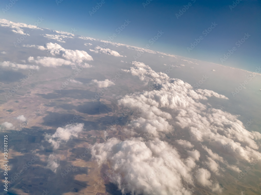 Fototapeta premium puffy clouds and earth view from above through airplane window