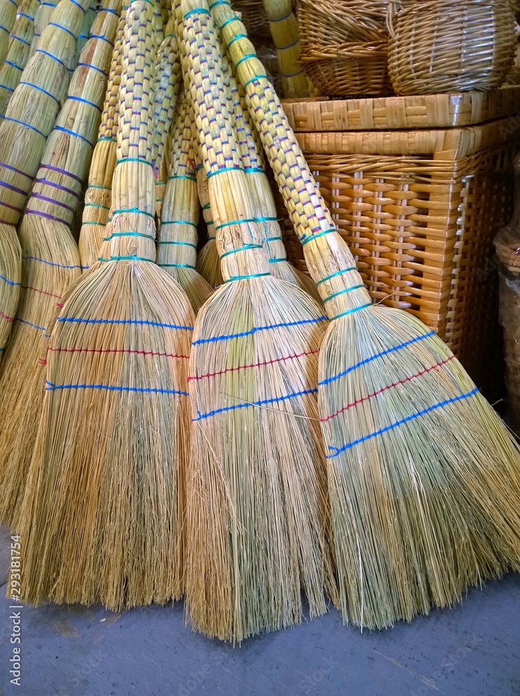 Handmade straw brooms for sale at a folk art fair. Country style interior decoration and a necessary craft object for cleaning the house.