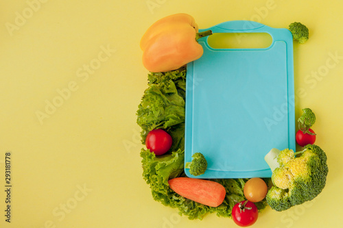 Blackboard with fresh vegetables on yellow background. Concept of Healthy Eating photo