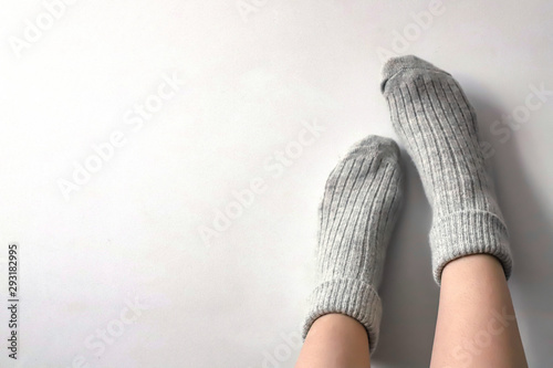 Women wearing grey knitted cozy socks on gray background. Сopyspace for text 