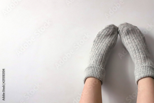 Women wearing grey knitted cozy socks on gray background. Сopyspace for text  photo