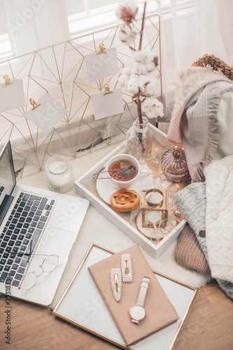 Toned photo. Autumn decor. A laptop, a mug of hot tea, a bun, candles. Cozy. Autumn.