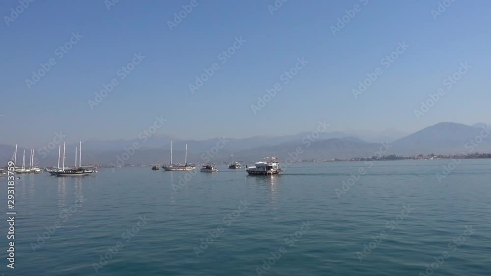 Beautiful ships and white yachts sail on a calm blue sea against a backdrop of small mountains on a Sunny summer day. Beautiful ships and white yachts sail on a calm blue sea against a backdrop of small mountains on a Sunny summer day.
