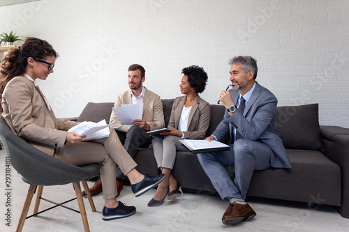Group of four people at office meeting sitting on sofa