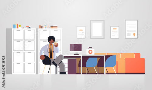 male doctor in white coat having coffee break medicine healthcare concept african american medical worker sitting at workplace modern hospital clinic office interior full length flat horizontal