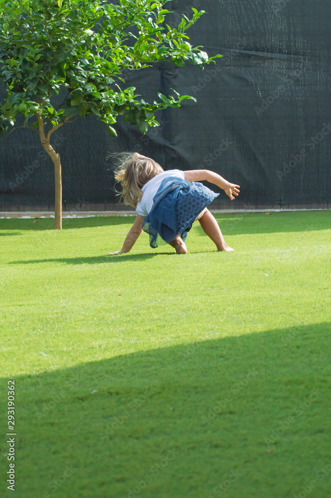 Obraz premium Niña rubia jugando en el césped / Little blonde girl playing on the grass