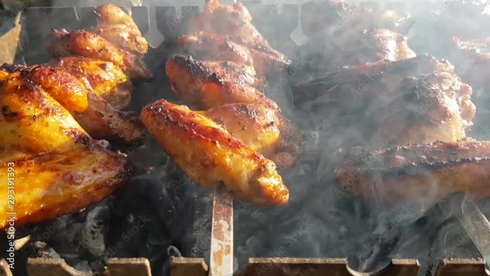 A close up of cooking chickens on the grill. Cooking grilled chicken wings. Barbecue food on the grill. Grilled summer cooking. The concept of relaxation, food, family and relaxation