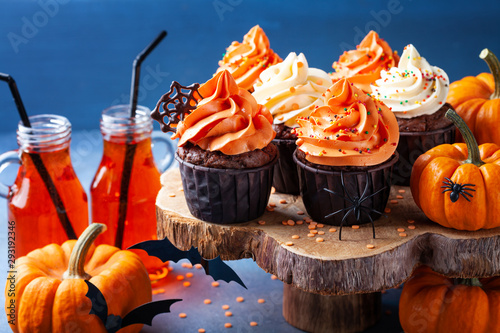 Halloween cupcakes and pumpkins on dark blue background. Sweets for holiday party.
