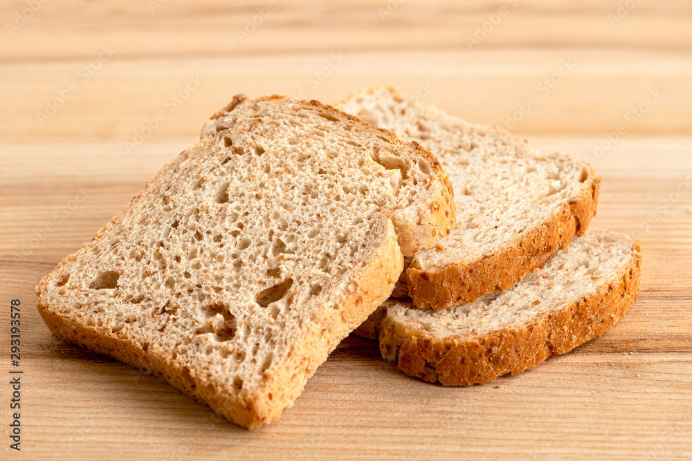 Three slices of whole wheat toast bread isolated on light wood.