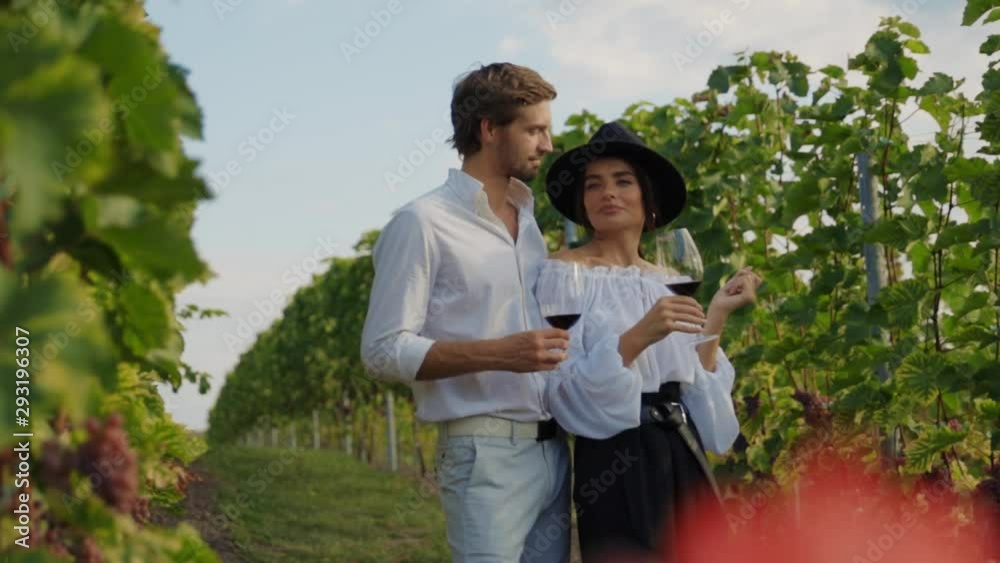 Beautiful elegant couple of man and woman drinking red wine enjoying holiday stay in vineyard valley. Young family on honeymoon tasting wine. Beautiful elegant couple of man and woman drinking red wine enjoying holiday stay in vineyard valley. Young family on honeymoon tasting wine.