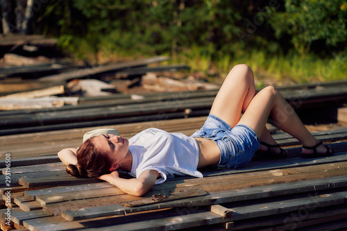 young woman lies on a pile of boards in the forest
