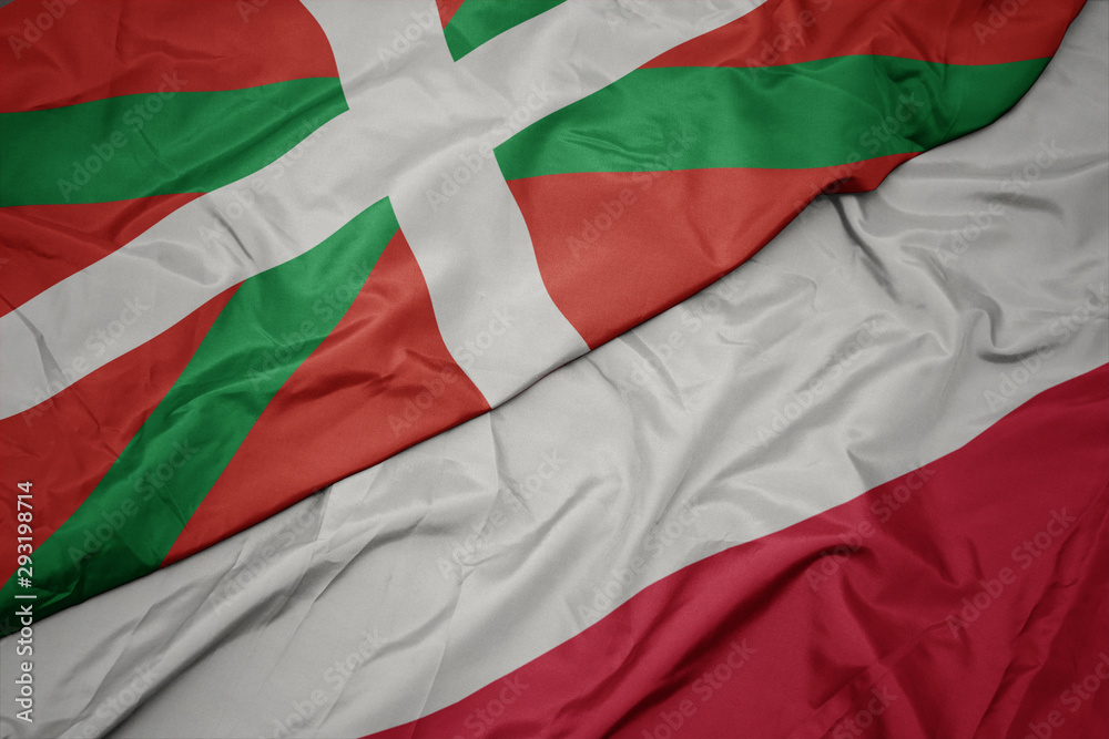waving colorful flag of poland and national flag of basque country.