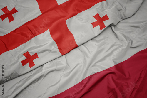 Fotografie waving colorful flag of poland and national flag of georgia.