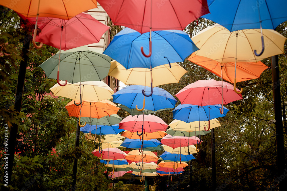 Texture. Lots of umbrellas hanging against the sky. Protection from sun and rain. Red, orange and blue.