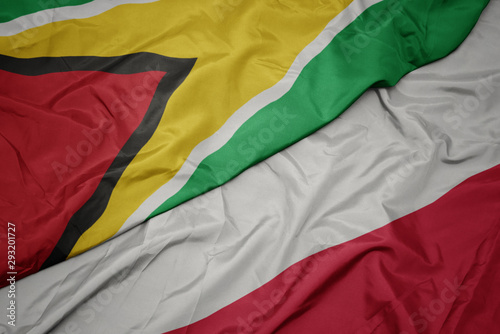 waving colorful flag of poland and national flag of guyana.