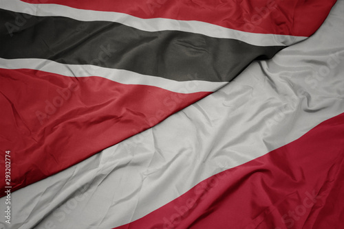 waving colorful flag of poland and national flag of trinidad and tobago.