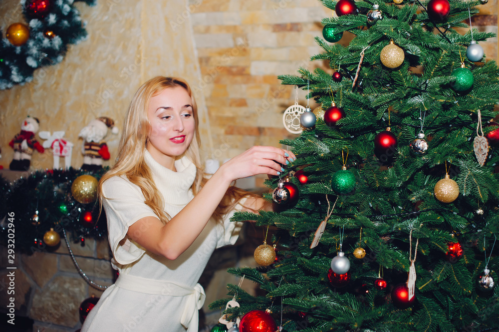 Beautiful girl in a decorated room. Woman near Christmas tree. Lady in a sweaters Beautiful girl in a decorated room. Woman near Christmas tree. Lady in a sweaters
