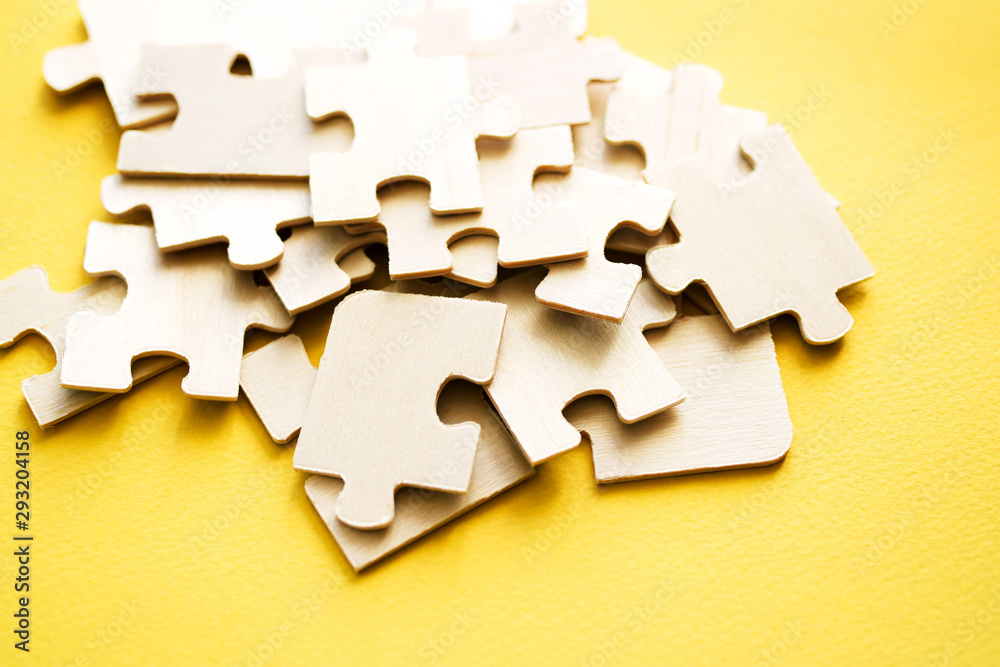 Fototapeta premium Wooden puzzles on a yellow background, closeup