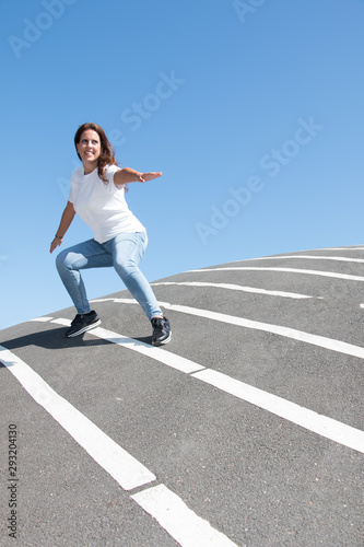 Smiling woman posing surfing over asphalt floor with white stripes